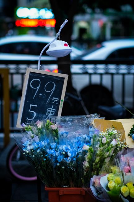 A display of fresh floral bouquets arranged in a red crate at a flower shop in Ruislip, featuring a variety of flowers including blue and pink blossoms with green foliage. The flowers are wrapped in c