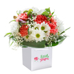 Like a promise of brighter days, this delightfully fresh bouquet stands ready to bring warmth to any South Ruislip doorstep. Expertly cradled in a chic white square gift bag, the ensemble dazzles with the joyful energy of coral and vibrant red carnations-their lush, frilled textures whispering of affectionate gestures and heartfelt surprises. Interwoven among these are pure white daisies, their glowing yellow-green eyes reminiscent of the first blooms in local parks once spring takes hold. Wisps of baby's breath lend an airy, cloudlike softness, while tucked-away hints of purple-laced buds add a touch of mystery. The sturdy yet graceful white handles promise effortless transport, making this bouquet perfect for brightening birthdays, congratulating milestones, or simply saying 'I'm thinking of you' across Ruislip Gardens or Bourne Avenue. Encircled by deep green, gleaming foliage, each petal and leaf is showcased by gentle natural light against the immaculate background, reflecting the care and dedication of South Ruislip's local florists in every thoughtful detail.